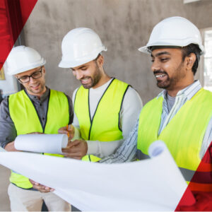Three people wearing safety gear looking at building plans.